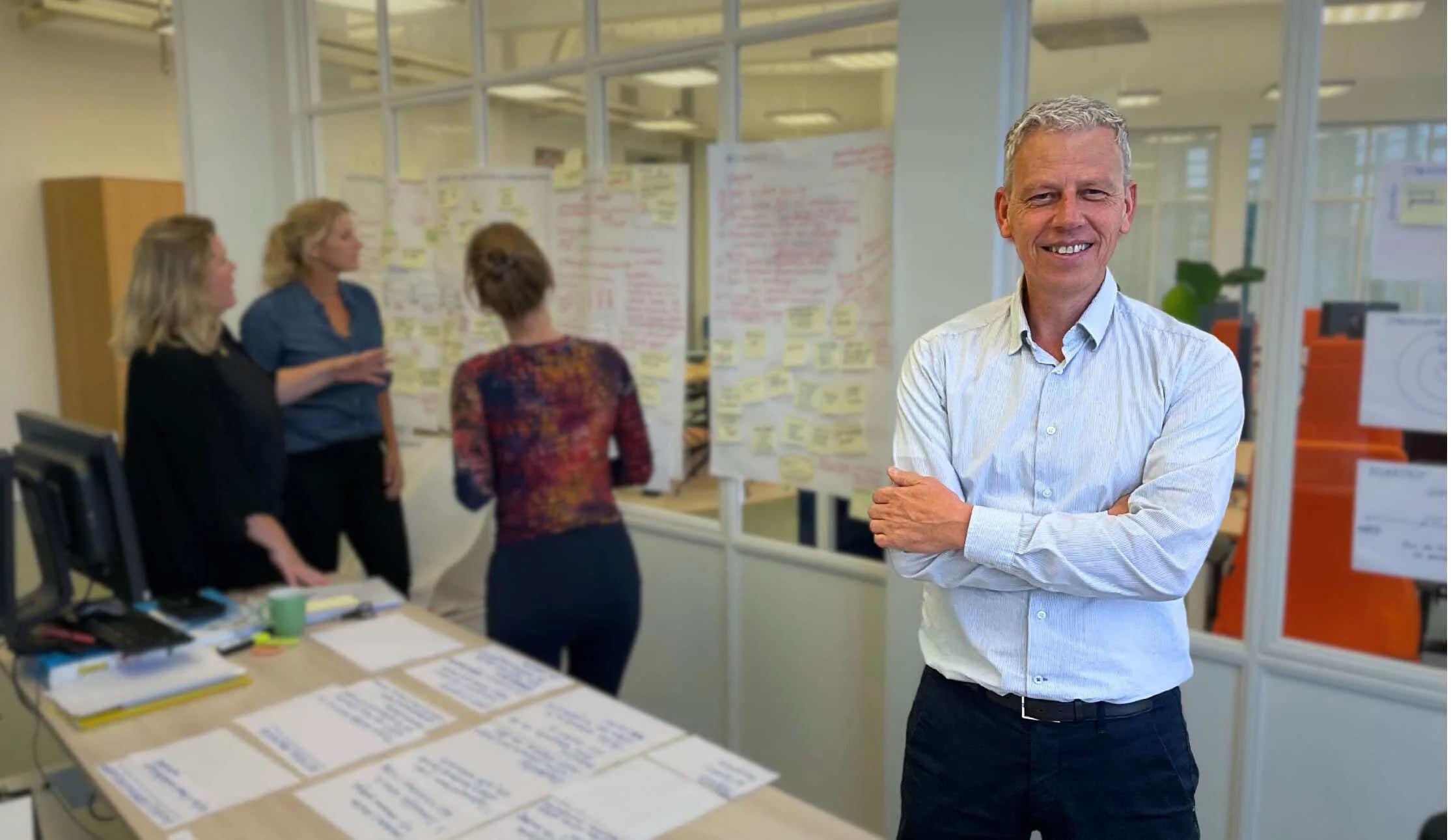 Peter Verheij in een werkruimte, met op de achtergrond mensen bij een whiteboard